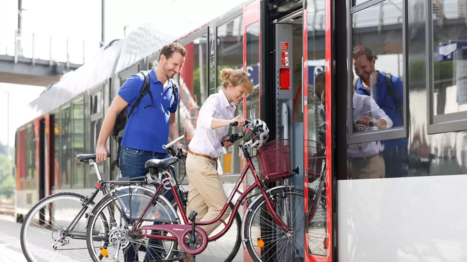 Zwei Fahrgäste steigen mit ihren Fahrrädern in einen Zug ein