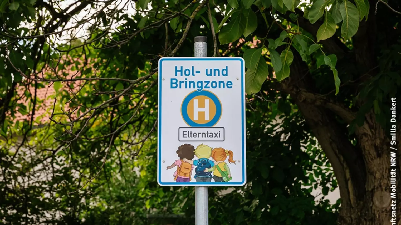 Blick auf ein Haltestellen-Schild mit der Aufschrift "Hol- und Bringzone Elterntaxi"