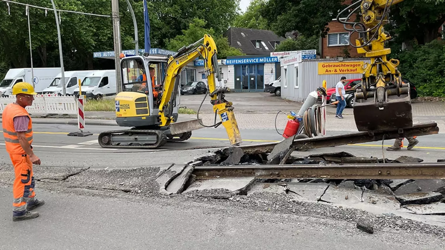 Neubau Haltestelle Brückelstraße: Zwei Baumaschinen nehmen alte Gleise auf, ein Bauarbeiter beobachtet die Arbeiten