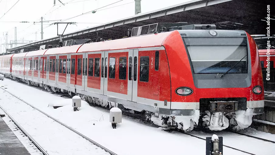 Eine Zug steht an einem verschneiten Bahnhof