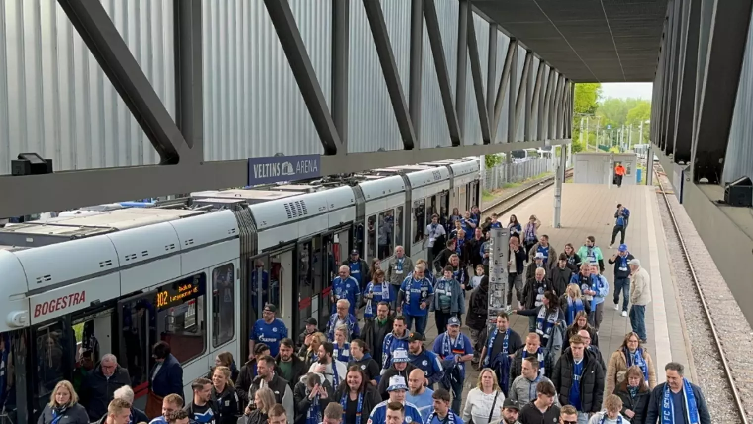 Fußballfans des FC Schalke 04 strömen aus den Straßenbahnen in Richtung Arena