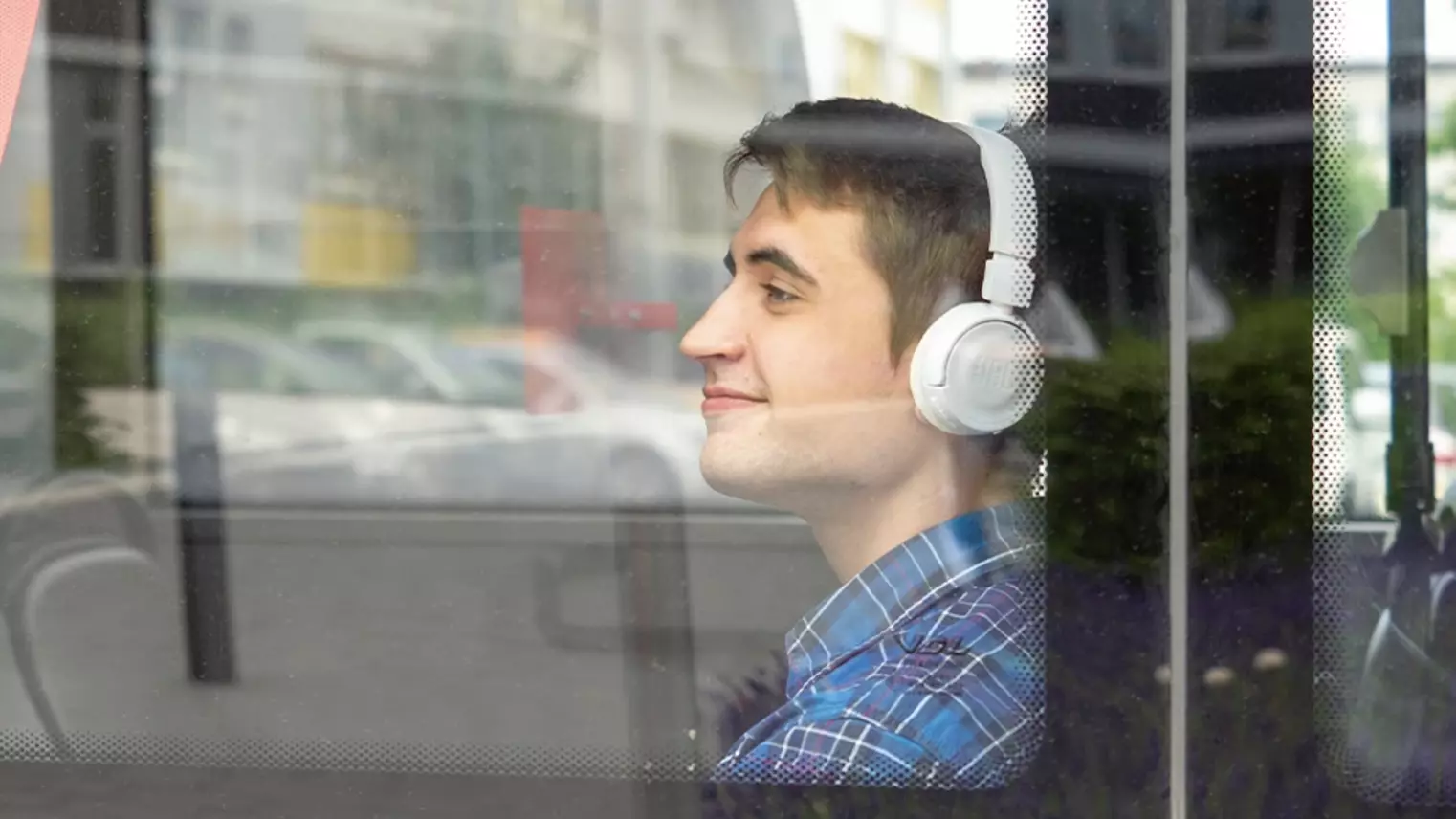 A young man sits on the bus wearing headphones