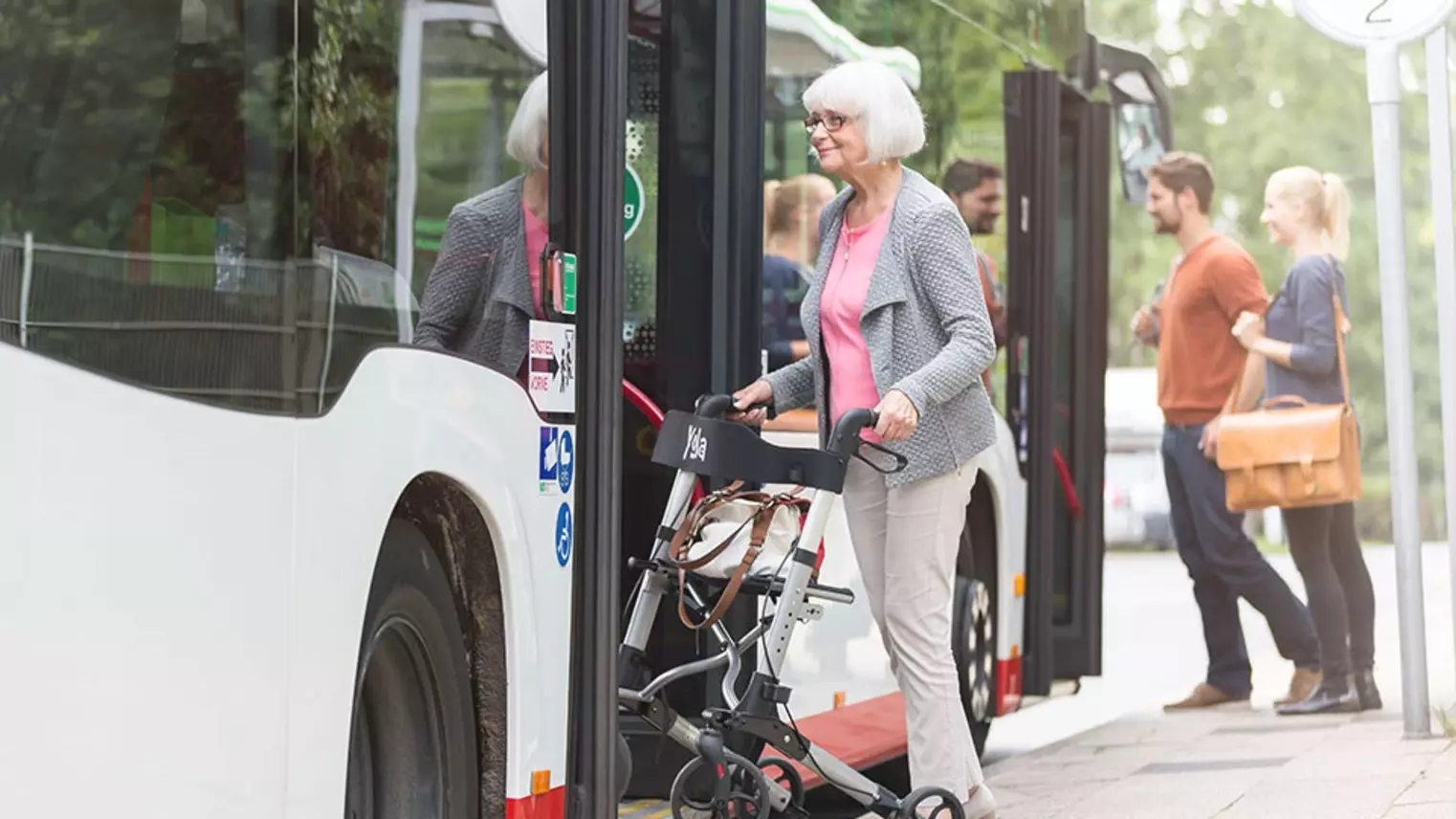 Eine ältere Frau steigt mit ihrem Rollator in den Bus ein