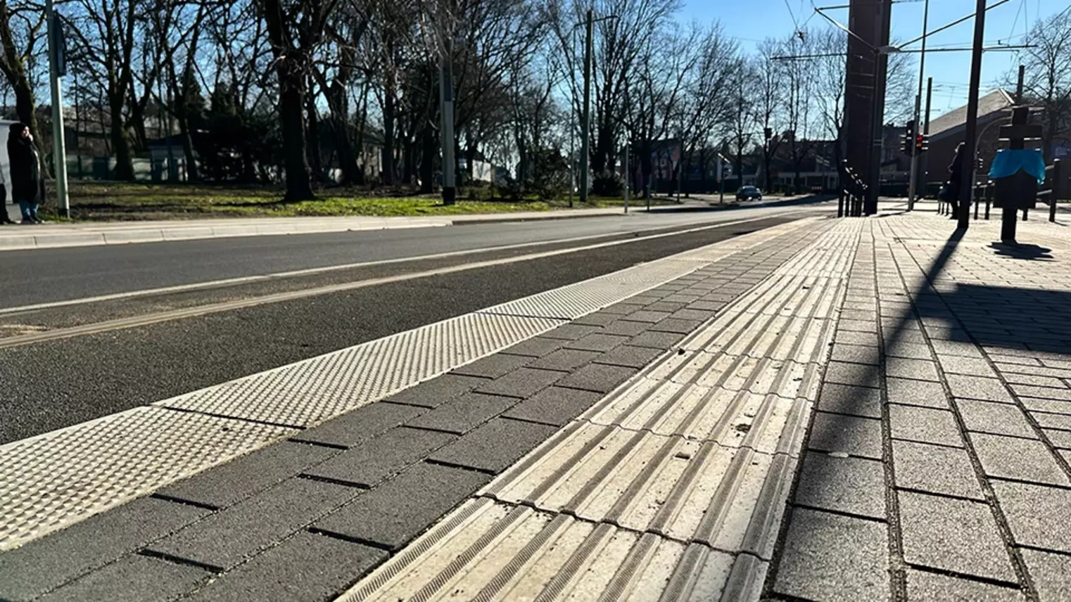 Neubau Haltestelle Brückelstraße: Detailaufnahme des fertigen Bahnsteigs mit taktilen Leitelementen, im Hintergrund sind Schienen und die Fahrbahn zu sehen