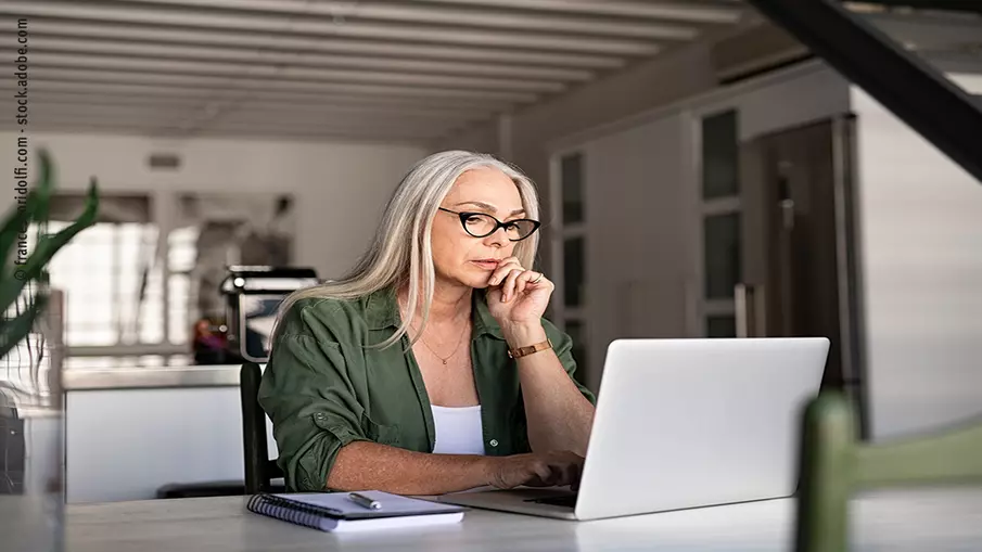 Frau sitzt an einem Tisch vor einem Laptop