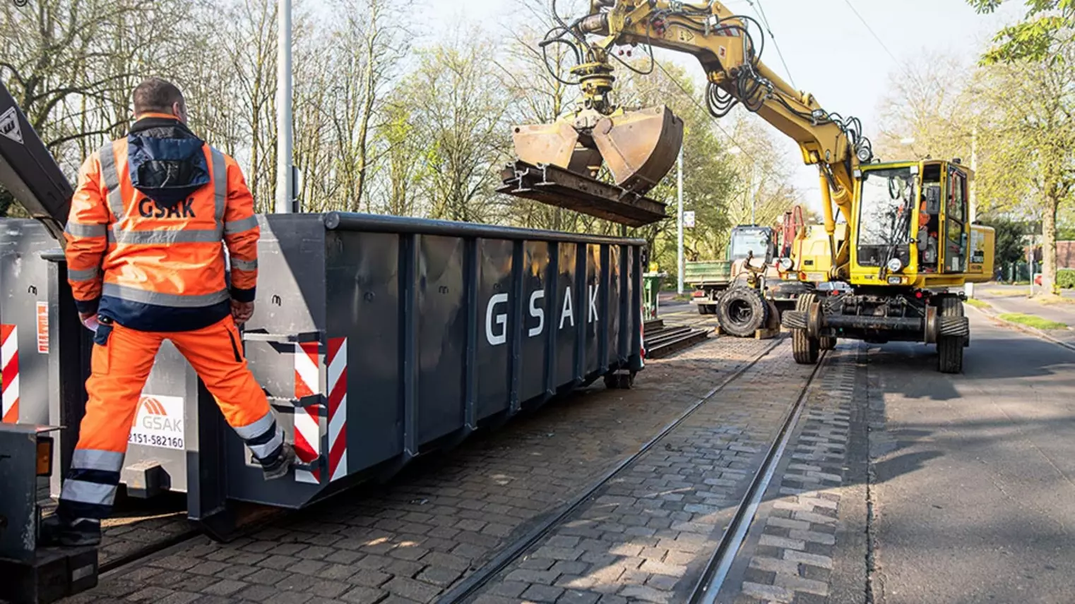 Ein Bagger entsorgt alte Gleise in einem Container