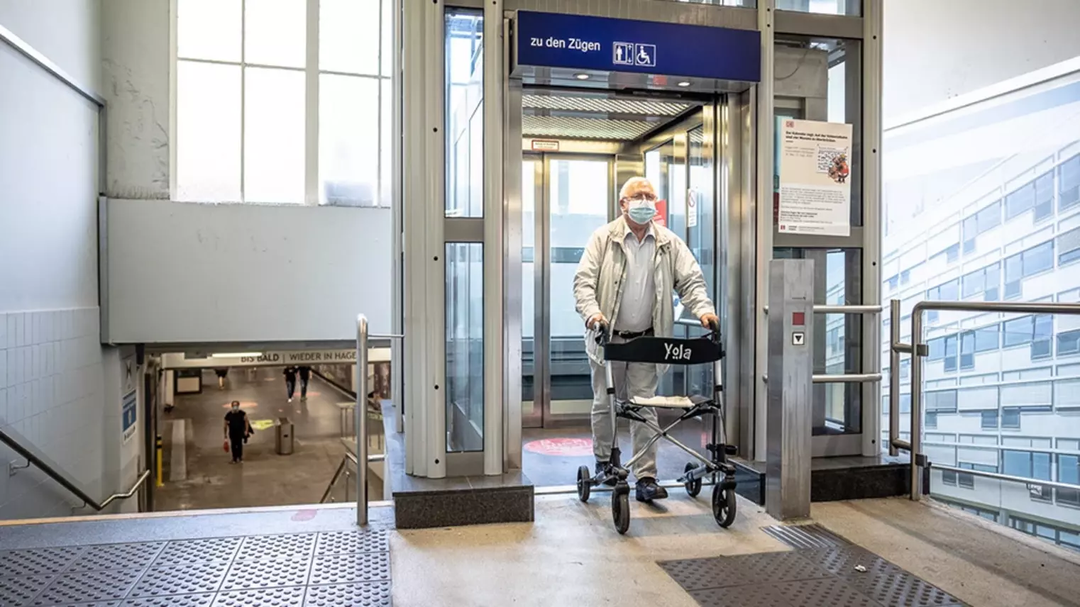 Ein Mann mit Rollator steigt aus einem Aufzug