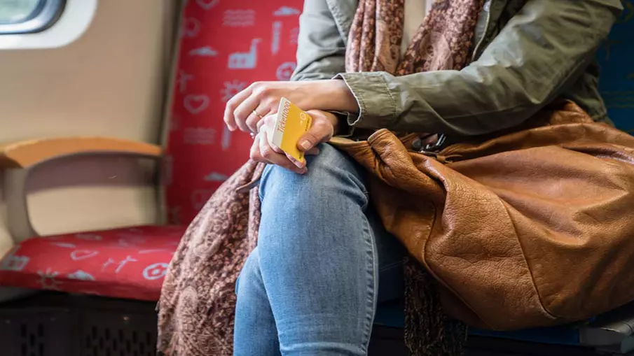 Eine Frau sitzt mit ihrem Ticket in der Hand im Zug