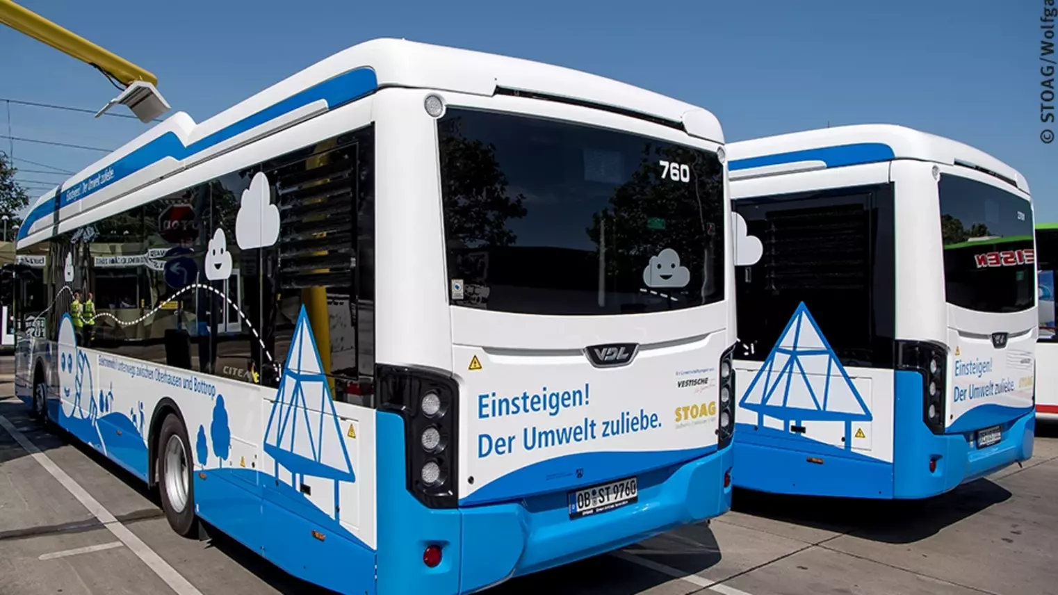 Zwei Elektrobusse der STOAG, über einem der Busse ist die Ladeinfrastruktur zu sehen