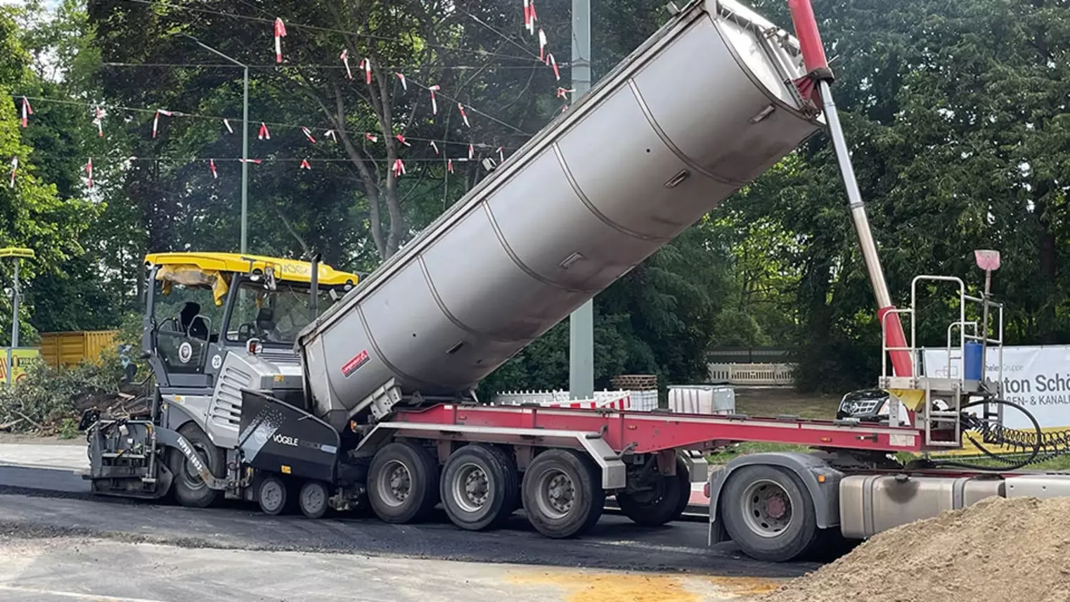 Neubau Haltestelle Brückelstraße: Asphaltierarbeiten, eine Baumaschine und ein Kipplaster sind zu sehen