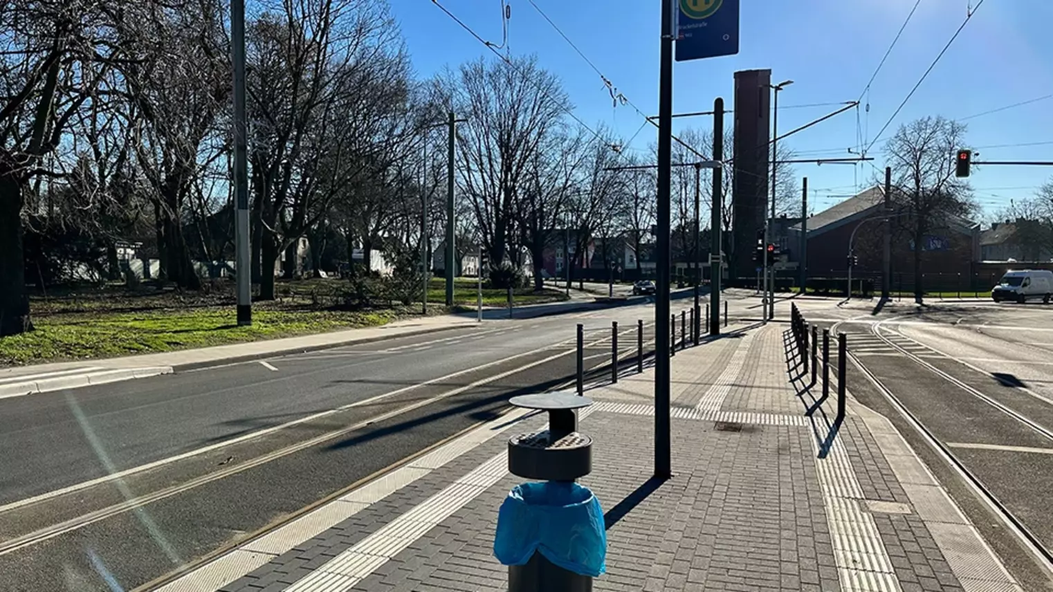 Neubau Haltestelle Brückelstraße: Blick auf einen Teil des fertigen Bahnsteigs mit der Rampe im Hintergrund, zu sehen ist ein Mülleimer, ein Haltestellenschilt und taktile Leitelemente