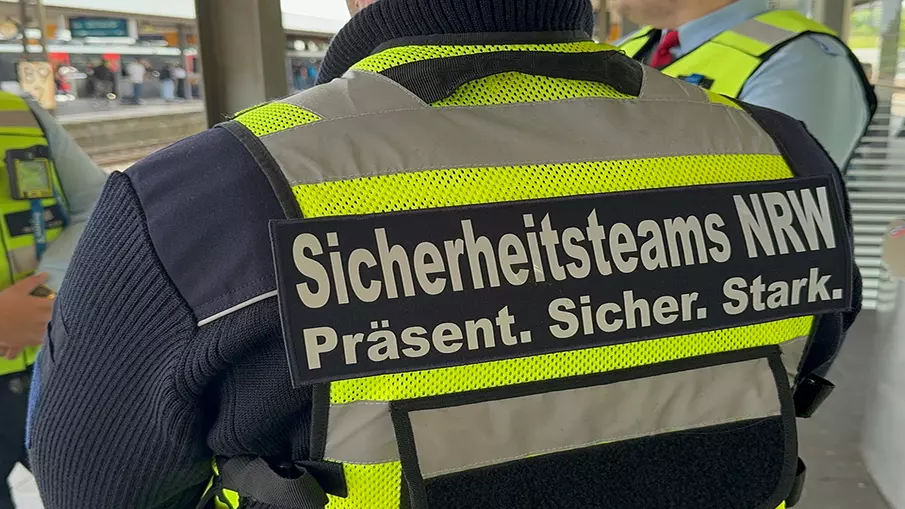 Eine Person von hinten mit dem Schriftzug "Sicherheitsteams NRW. Präsent. Sicher. Stark"