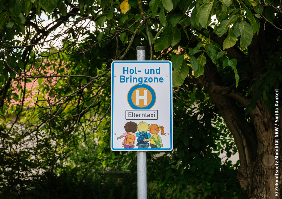 Blick auf ein Haltestellen-Schild mit der Aufschrift "Hol- und Bringzone Elterntaxi"