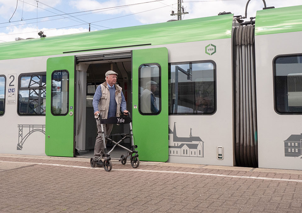 Ein älterer Herr mit Rollator steigt barrierefrei mit Rollator aus einer S-Bahn