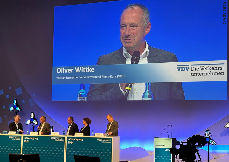 Blick auf die Bühne des Forum "ÖPNV", auf einer Leinwand ist VRR-Vorstandssprecher Oliver Wittke zu sehen